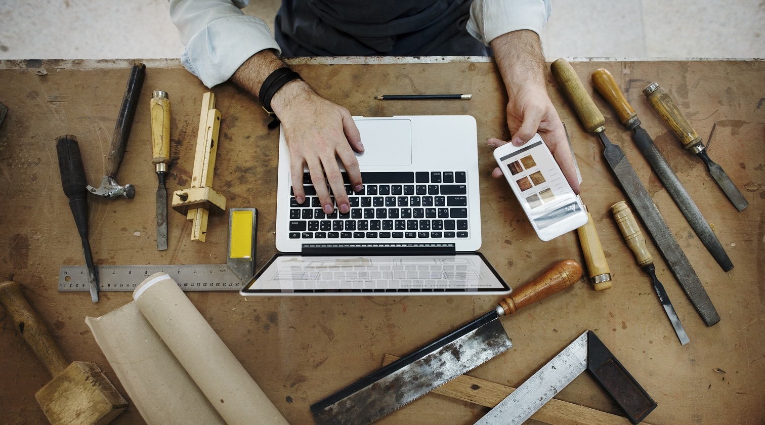 artesão com ferramentas usa o computador e o celular
