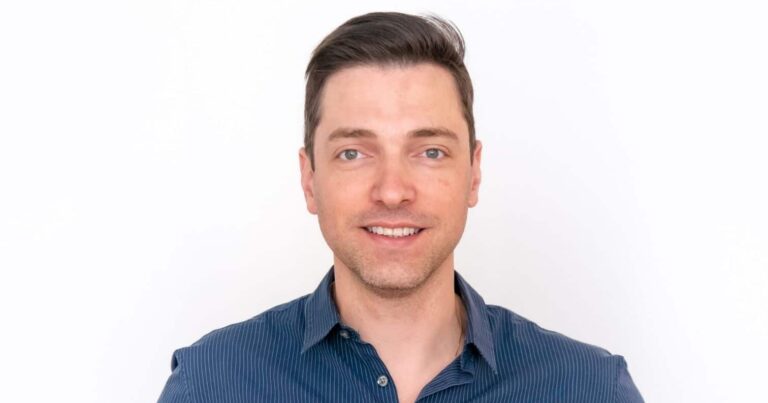 Rodrigo Rodrigues, CTO global da Serasa Experian, em um retrato profissional. Ele está sorrindo levemente, veste uma camisa social azul e tem cabelos curtos e castanhos. O fundo branco destaca sua imagem, conferindo um tom clean e corporativo à fotografia.