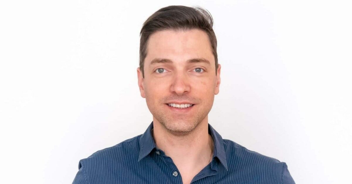 Rodrigo Rodrigues, CTO global da Serasa Experian, em um retrato profissional. Ele está sorrindo levemente, veste uma camisa social azul e tem cabelos curtos e castanhos. O fundo branco destaca sua imagem, conferindo um tom clean e corporativo à fotografia.