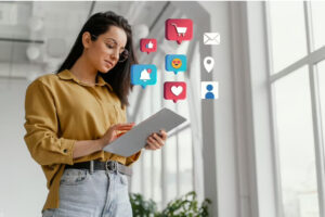 Mulher mexendo em tablet enquanto ícones relacionados à redes sociais são projetados para fora da tela. 