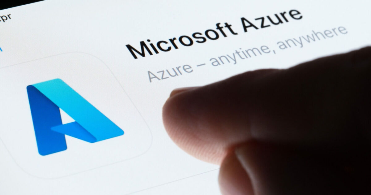 Imagem em close de um dedo tocando a tela de um dispositivo exibindo o ícone azul da Microsoft Azure e o texto 'Microsoft Azure – anytime, anywhere', representando o serviço de nuvem da Microsoft