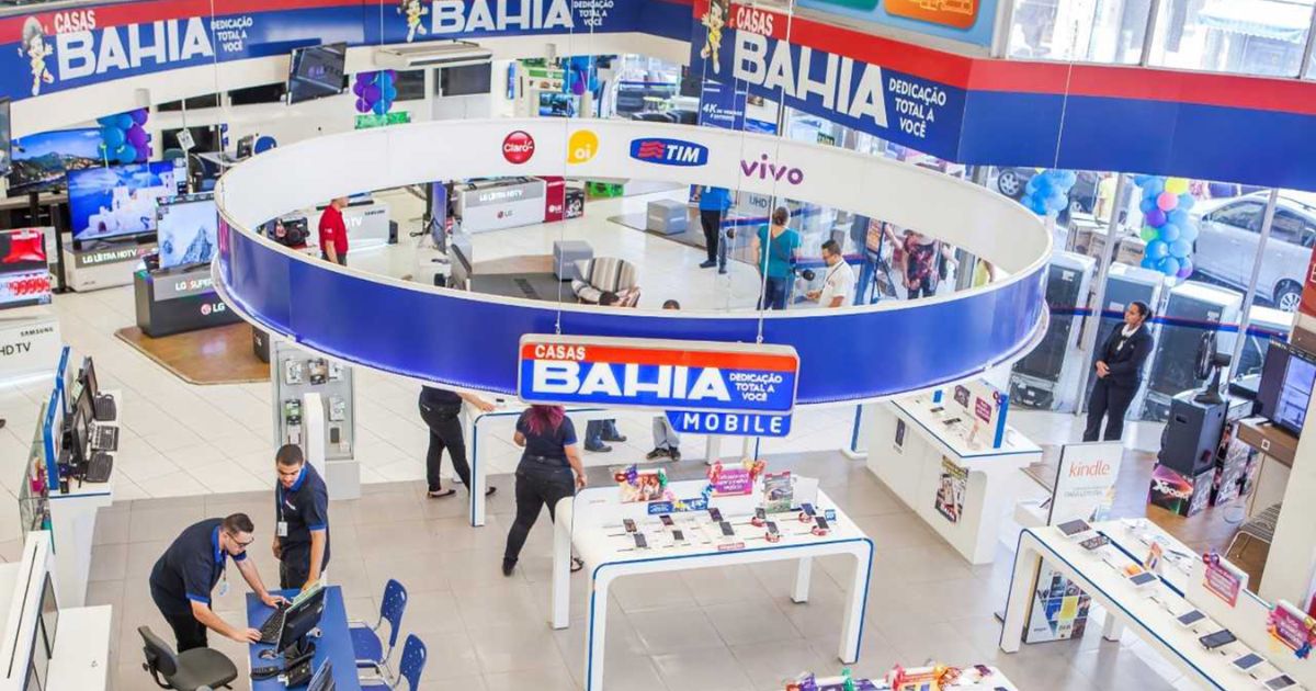 Interior de uma loja das Casas Bahia, com diversos produtos eletrônicos expostos, como televisores, smartphones e acessórios. O ambiente é organizado e iluminado, com funcionários atendendo clientes. No centro, destaque para a área de tecnologia e um grande letreiro azul com o logotipo das Casas Bahia (casas bahia, black friday, pagamento)
