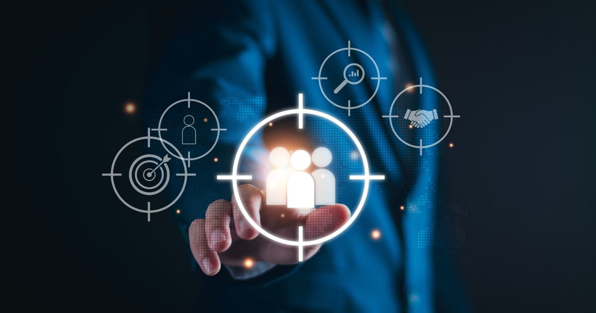 Texto alternativo: Pessoa vestindo um terno azul tocando uma tela virtual com um ícone de grupo de pessoas dentro de uma mira digital. Ao redor, há outros ícones representando alvos, análise de dados, pesquisa e aperto de mãos, simbolizando estratégias de gestão de clientes e marketing direcionado. O fundo é escuro com um efeito tecnológico e futurista. (Gestão, clientes, tecnoloiga, negócios, preparado identificar, hiperpersonalização, continuidade)