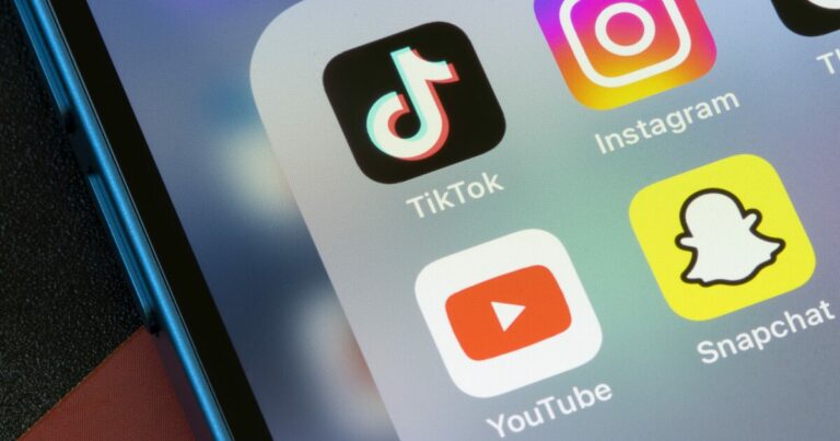 Imagem mostra a tela de um smartphone com os ícones dos aplicativos TikTok, Instagram, YouTube e Snapchat, organizados em uma pasta. O aparelho possui borda azul metálica e está sobre uma superfície escura.(União Europeia, Kaspersky)