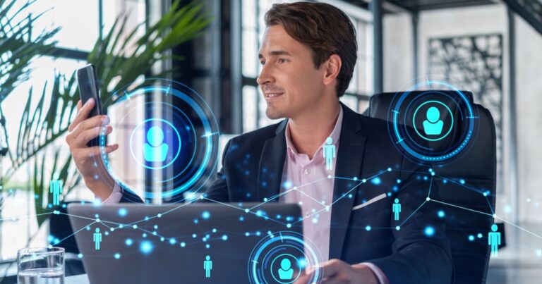 A imagem mostra um executivo sentado em frente a um laptop, sorrindo enquanto olha para um smartphone. No ambiente ao redor, há gráficos digitais e ícones representando pessoas conectadas, sugerindo um contexto relacionado à gestão de pessoas e tecnologia, como em recursos humanos ou rede de colaboradores. A cena transmite uma atmosfera moderna e inovadora, com o uso de tecnologia para gerenciar equipes ou interagir com sistemas de comunicação e conectividade. O ambiente tem um design contemporâneo, com plantas e grandes janelas ao fundo (rh, recursos humanos, gestão, pessoas, pessoal, gestor, homem branco, executivo, CEOs)