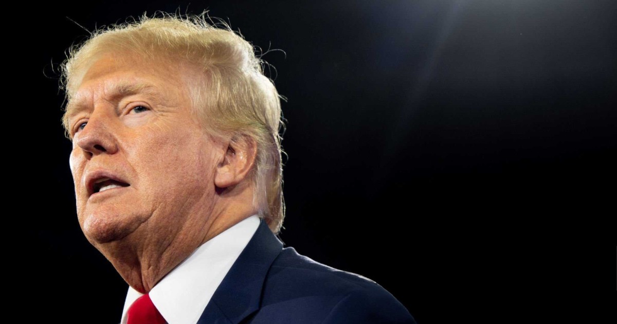 Imagem de Donald Trump, presidente dos Estados Unidos, com cabelos loiros, expressão séria e usando traje formal com terno azul e gravata vermelha, capturado contra um fundo escuro com iluminação destacando seu rosto (infraestrutura)