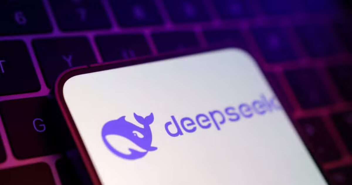 Logotipo da empresa DeepSeek exibido na tela de um smartphone, com o aparelho apoiado sobre um teclado de computador iluminado por luzes roxas