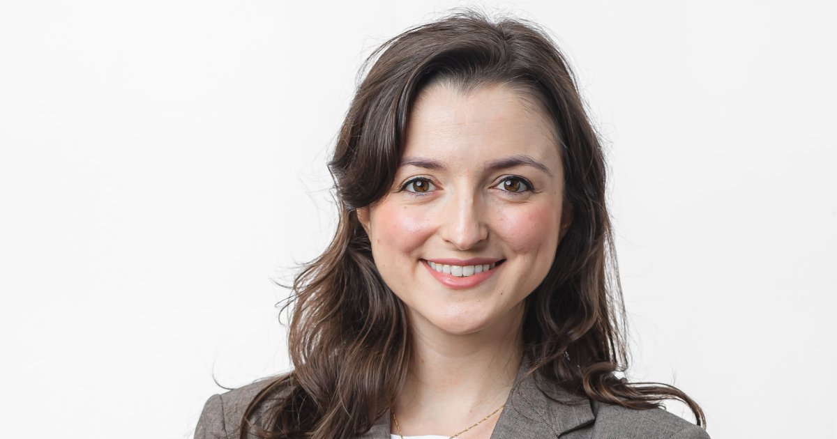 Retrato de Fernanda Konradt de Campos, do Centro de Empreendedorismo Inovador da CERTI. Ela está sorrindo, com cabelos castanhos ondulados e veste um blazer cinza. O fundo branco realça sua expressão simpática e profissional