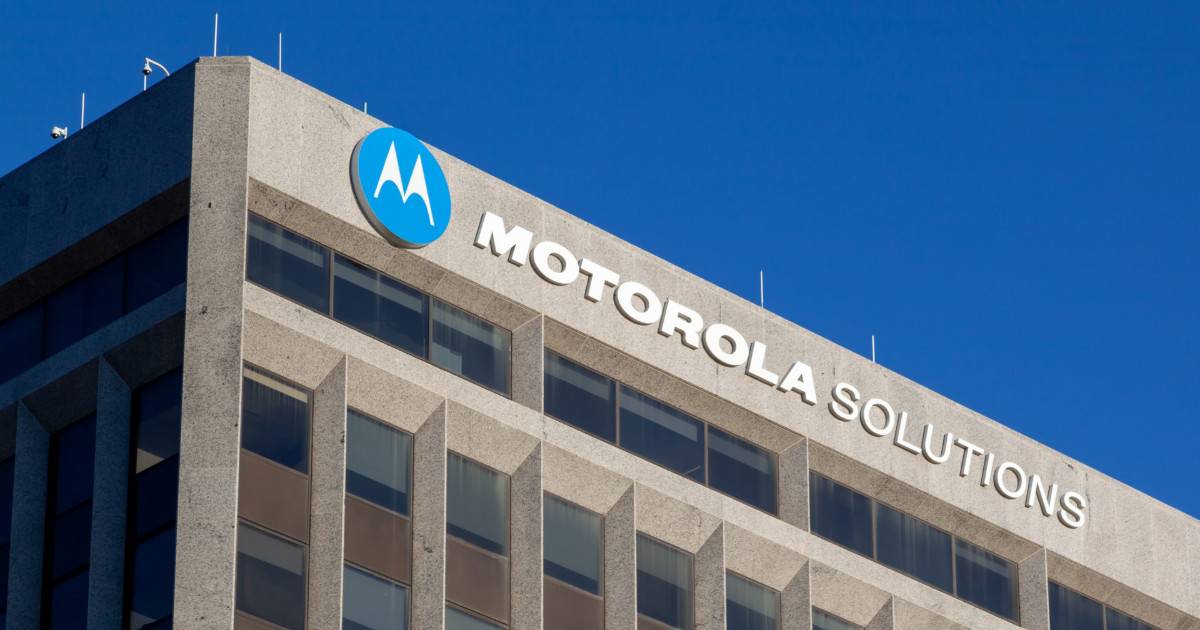 Fachada de um prédio corporativo com o logotipo da Motorola Solutions em destaque, sobre um céu azul claro, hytera
