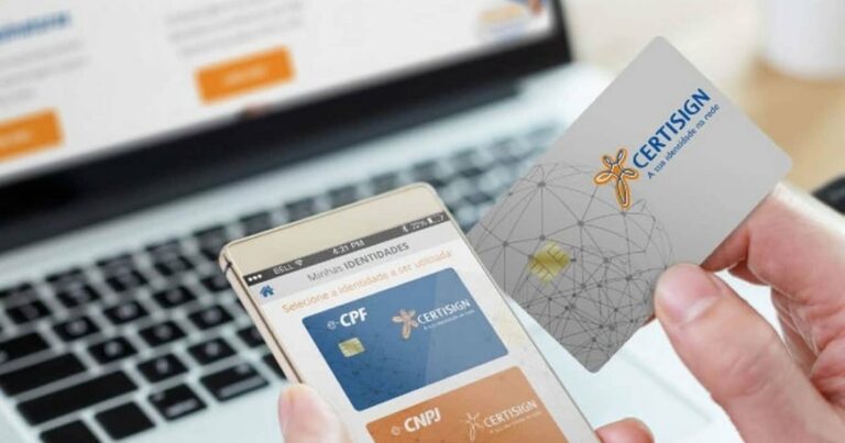 Imagem mostrando uma pessoa segurando um cartão de certificação digital da Certisign e um smartphone com um aplicativo aberto, exibindo opções de identidade digital para CPF e CNPJ. Ao fundo, há um notebook com uma tela desfocada