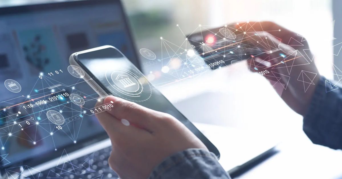 Pessoa segurando um smartphone e um cartão de crédito, com elementos gráficos digitais representando transações financeiras, tecnologia bancária e conexões de dados. Ao fundo, um notebook desfocado. A imagem simboliza fintechs, digitalização de serviços financeiros e pagamentos online (fintech, finanças, bancarização, cartão, serviços financeiros, setor financeiro, cartões)