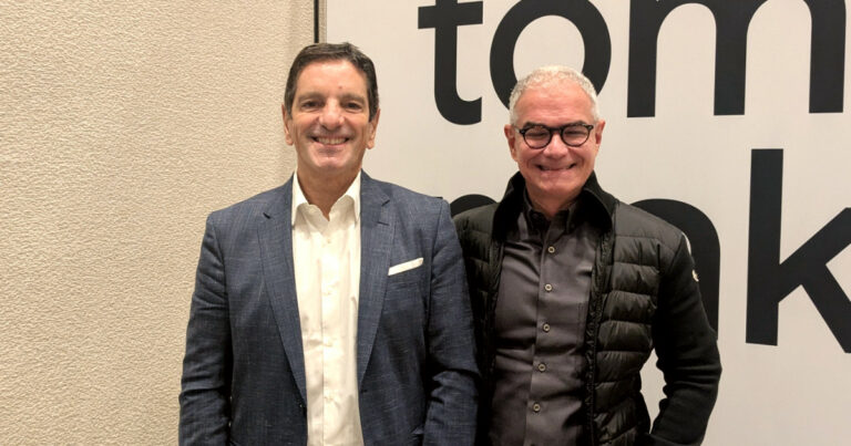 Ricardo Fernandes, presidente do Google Cloud para a América Latina, e Eduardo Lopes, head do Google Cloud Brasil, posam sorridentes lado a lado. Ricardo Fernandes veste paletó azul e camisa branca, enquanto Eduardo Lopes usa óculos, camisa escura e jaqueta preta. Ao fundo, parte de uma parede clara e parte de um painel com letras grandes em preto (nuvem)