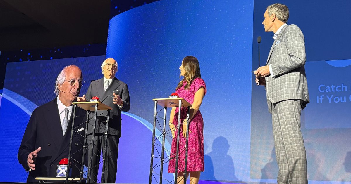 Frank Abagnale, Tatiana Zambrano e o moderador participam de um game show temático no palco do SAS Innovate 2025. Em frente a púlpitos com botões vermelhos, o trio debate fraudes financeiras com leveza e profundidade. Ao fundo, o telão exibe o nome da sessão: "Catch Me If You Can".