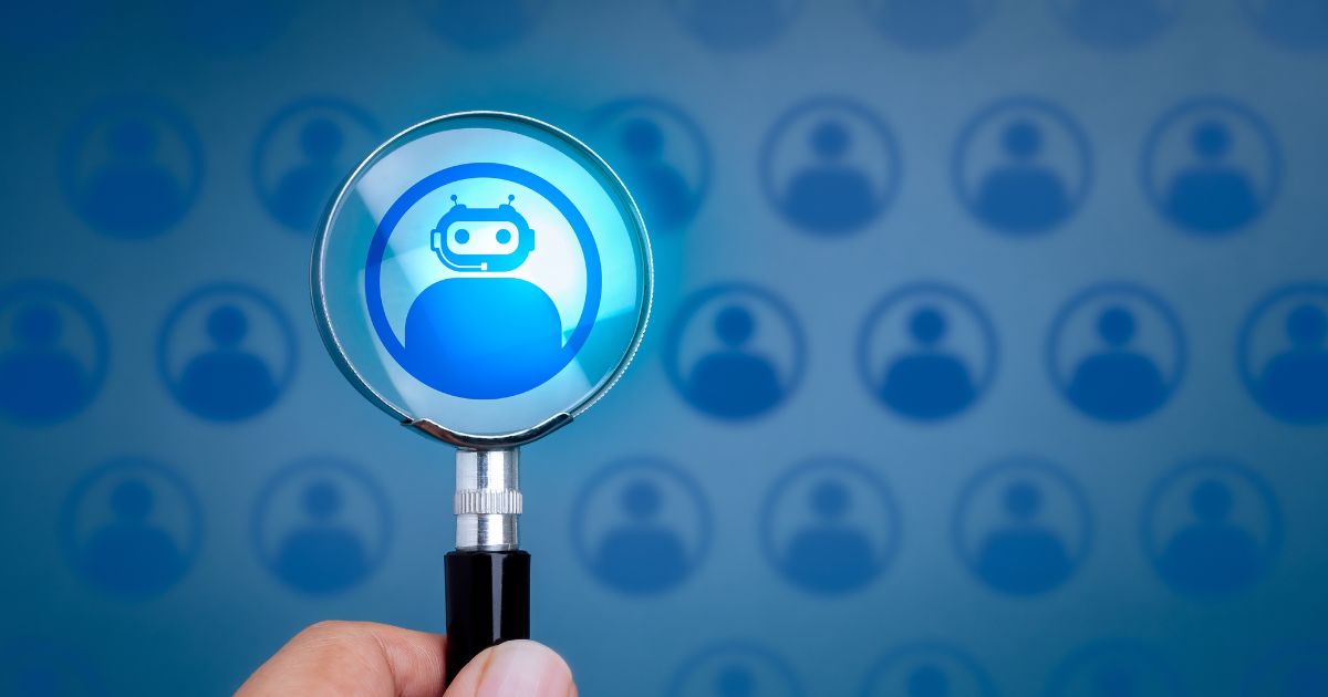 Imagem conceptual de seleção de perfis com foco em inteligência artificial. Uma mão segura uma lupa que destaca um ícone de robô azul dentro de um círculo, representando um perfil de IA. Ao fundo, vários ícones semelhantes de perfis humanos aparecem desfocados, também em tons de azul. A lupa simboliza a escolha ou identificação de uma inteligência artificial entre perfis humanos.