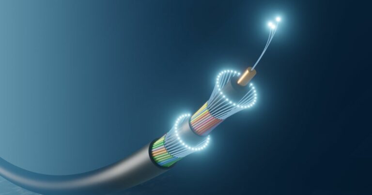Imagem ilustrativa de um cabo submarino de fibra óptica, utilizado em telecomunicações. A imagem mostra o cabo cortado em perspectiva para exibir sua estrutura interna, com várias camadas de proteção e múltiplas fibras ópticas brilhando em azul, indicando a transmissão de dados por luz. O fundo azul escuro simula o ambiente subaquático (cabo submarino, fibra óptica, telecomunicações)
