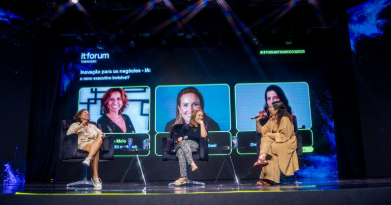 Graci de Melo, fundadora e coCEO da V8, e Priscyla Laham, presidente da Microsoft Brasil, participam de um painel no IT Forum Trancoso 2025. As duas estão sentadas em poltronas no palco, conversando com uma mediadora que segura um microfone. Ao fundo, a tela exibe o tema “Inovação para os negócios – IA: o novo executivo invisível?” junto com as fotos e cargos das participantes, organizações