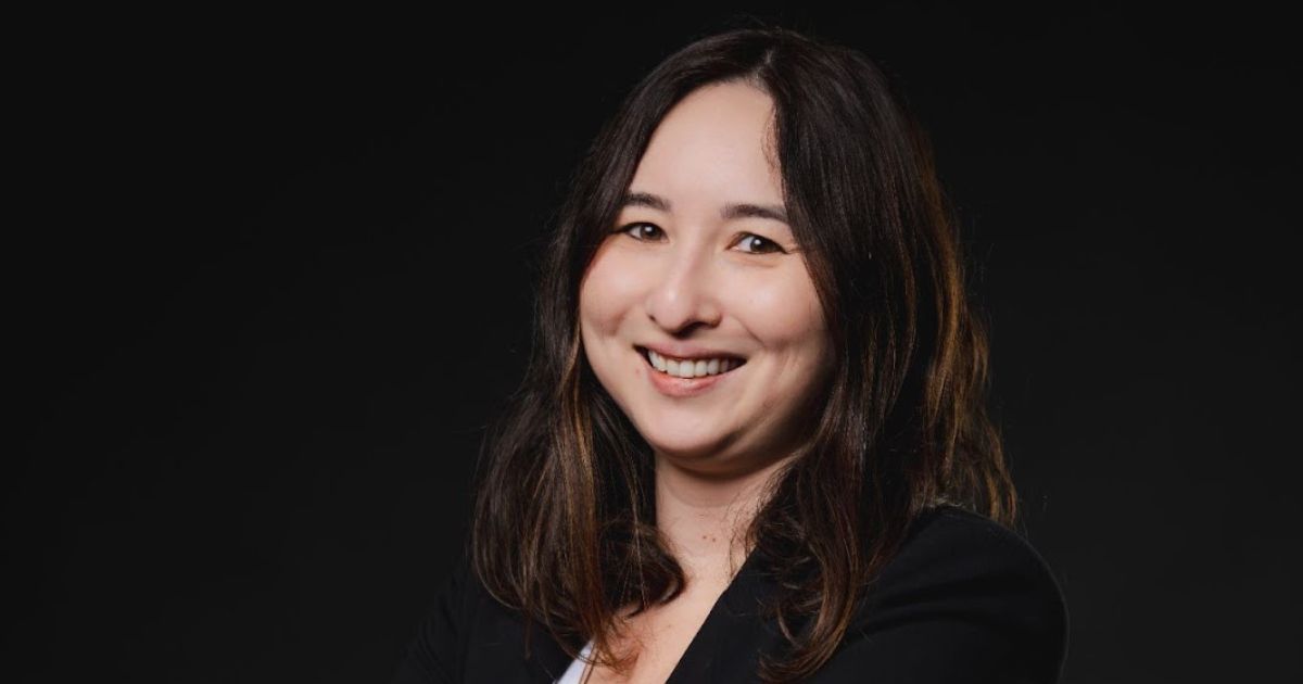 Uma pessoa de cabelos longos, vestindo um blazer de cor escura, está posicionada contra um fundo preto. O rosto da pessoa está desfocado, tornando-a não identificável. (Omni Saúde)