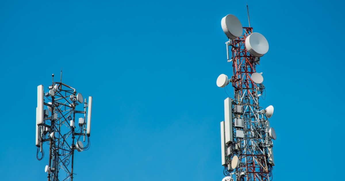 Duas torres de telecomunicação equipadas com diversas antenas e receptores, usadas para transmissão de sinais de rede, como 4G. As estruturas metálicas estão posicionadas contra um céu azul claro, representando infraestrutura de comunicação e conectividade móvel (rodovias)