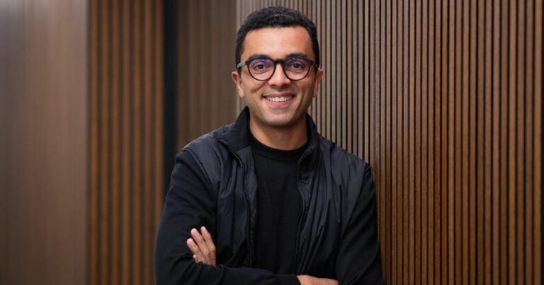 Hugo Tadeu, diretor do núcleo de inovação, inteligência artificial e tecnologias digitais da Fundação Dom Cabral (FDC) está em pé com os braços cruzados, encostada em uma parede com ripas verticais de madeira. Não há elementos visíveis relacionados a problemas de matemática ou tarefas escolares. (Brasil)