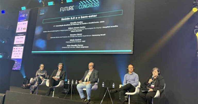 A imagem mostra um painel de discussão durante o evento "Future Congress". No palco, cinco pessoas estão sentadas em cadeiras, com microfones e garrafas de água à frente. Ao fundo, uma tela exibe o título da palestra: "Saúde 5.0 e o bem-estar", junto aos nomes e cargos dos participantes: Claudio Coelho, VP da Associação Brasileira de Empresas de Saúde e healthTeacher – ABSS Edson Amaro Junior, Médico Neurorradiologista e Pesquisador em Tecnologias Avançadas para Equidade – Hospital Israelita Albert Einstein Renato Citrini, Gerente Sênior de Produto na Divisão de Mobile Experience – Samsung Brasil Silvia Cabral, Distinguished Analyst – TDT Ana Claudia Ferrari, Diretora de Vendas – Eficaz Empresas O ambiente é formal, voltado para uma apresentação sobre avanços em saúde e bem-estar.