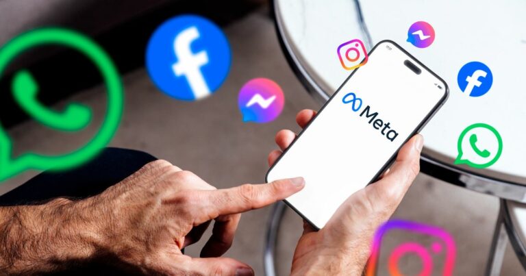 A imagem mostra uma mão segurando um smartphone que exibe o logotipo da Meta em destaque, com o texto “Meta” e o símbolo característico da empresa. Ao redor do dispositivo, há ícones flutuantes representando os principais aplicativos do ecossistema Meta: WhatsApp (ícones verdes com balão de conversa) Facebook (ícones azuis com a letra “f”) Instagram (ícones coloridos em tons de rosa, roxo e laranja) Messenger (ícones azuis com balão de mensagem) O fundo é neutro, com uma mesa metálica parcialmente visível, sugerindo um ambiente casual ou corporativo. A composição transmite a ideia de conectividade e integração entre as plataformas da Meta, reforçando sua presença no universo digital. redes sociais