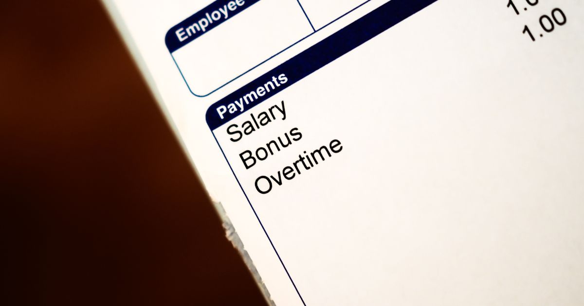 A imagem mostra uma parte de um documento impresso, provavelmente um contracheque ou folha de pagamento. Em destaque, há uma seção com o título “Payments” (Pagamentos), seguida por três itens listados: Salary (Salário), Bonus (Bônus) e Overtime (Horas extras). Acima, parcialmente visível, está outra seção com a palavra Employee (Empregado) e alguns números à direita, indicando valores ou quantidades. O fundo é branco, com texto em preto e azul, transmitindo um aspecto formal e corporativo. (caixa)