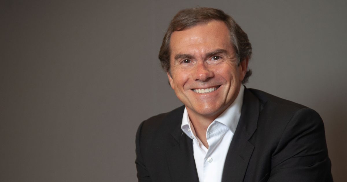 Um homem está posicionado diante de um fundo cinza uniforme, vestindo um terno preto sobre uma camisa social branca. A imagem é enquadrada da altura do peito para cima, com iluminação suave que realça as cores neutras da roupa e do ambiente, transmitindo um tom formal e profissional. (Diego Puerta, presidente da Dell Technologies Brasil)