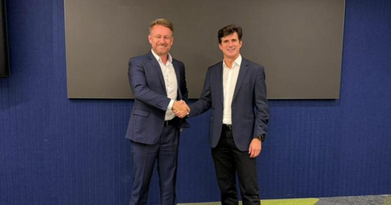 A imagem mostra duas pessoas vestindo ternos formais, realizando um aperto de mão em um ambiente corporativo. Aqui estão os principais detalhes: Configuração geral: Ambos estão posicionados lado a lado, com postura ereta, reforçando um gesto de parceria ou acordo profissional. Vestimenta: Trajes formais compostos por ternos escuros e camisas brancas, transmitindo seriedade e profissionalismo. Ambiente: Fundo com uma parede azul e um painel retangular preto, sugerindo um espaço interno moderno, possivelmente uma sala de reuniões ou área corporativa. Composição: O aperto de mão é o elemento central, simbolizando colaboração, networking ou fechamento de negócio. Essa imagem é ideal para representar parcerias estratégicas, acordos corporativos ou momentos importantes de conexão profissional. (NTT Data)