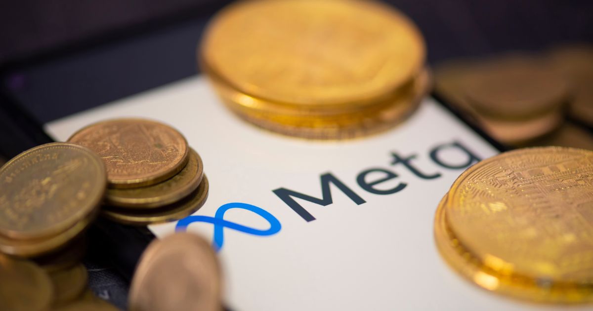 Imagem mostrando várias moedas douradas espalhadas sobre uma superfície onde aparece parcialmente o logotipo da Meta. As moedas estão desfocadas em alguns pontos, enquanto o nome “Meta” e o símbolo em azul ficam visíveis ao centro.
