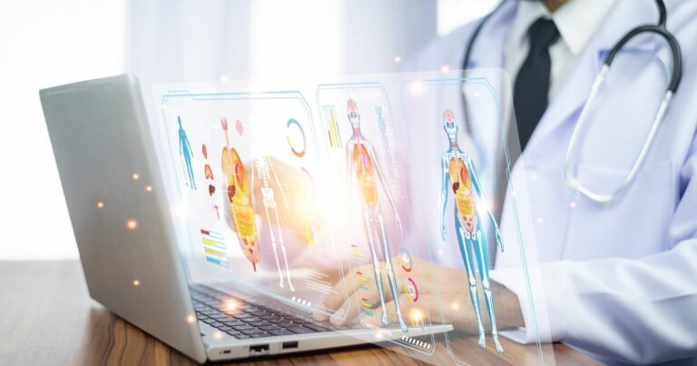 Profissional da área da saúde usando jaleco e estetoscópio trabalha em um notebook sobre uma mesa de madeira. À frente da tela, gráficos e painéis digitais em estilo holográfico exibem modelos anatômicos do corpo humano, órgãos internos e indicadores médicos, representando análise clínica avançada e uso de tecnologia digital na medicina. (Fundação Gates)