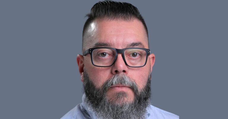 Pessoa vestindo camisa social clara, posicionada de frente para a câmera contra um fundo uniforme em tom cinza. O enquadramento é centralizado e destaca a parte superior do tronco, incluindo a gola da camisa e parte da barba, transmitindo um contexto profissional e neutro. (Luiz Eduardo, CTO Global de Segurança da HPE Networking)