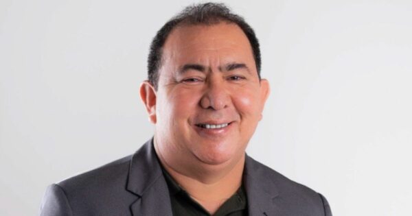 A imagem mostra uma pessoa vestindo um blazer escuro sobre uma camisa polo preta. O fundo é simples e de cor clara, provavelmente branco ou cinza claro, com iluminação uniforme, sugerindo um ambiente de estúdio ou foto profissional. A composição transmite uma aparência formal ou corporativa, típica de retratos usados para perfis profissionais ou institucionais. (startups)