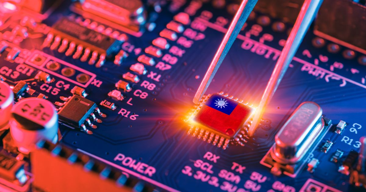 Uma placa-mãe eletrônica é mostrada em close, com destaque para um microchip vermelho que exibe o desenho de um sol estilizado em branco. Um par de pinças metálicas segura cuidadosamente o chip enquanto ele brilha com um efeito de luz intensa, sugerindo instalação ou remoção. A placa possui diversos componentes, como capacitores, resistores e trilhas azuis iluminadas por tons vibrantes de rosa e laranja, criando um visual tecnológico e dinâmico.