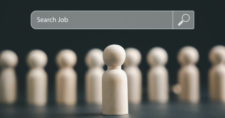 Uma peça central em forma de boneco de madeira está posicionada em destaque, enquanto várias figuras semelhantes aparecem desfocadas ao fundo. Na parte superior da imagem, há uma barra de busca estilizada com o texto “Search Job” acompanhado do ícone de uma lupa, transmitindo a ideia de procura por vagas ou oportunidades profissionais, como CIO's. (tecnologia)