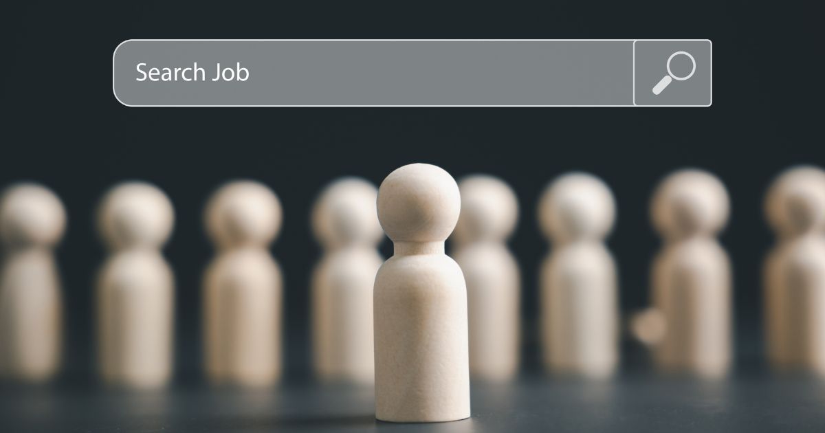 Uma peça central em forma de boneco de madeira está posicionada em destaque, enquanto várias figuras semelhantes aparecem desfocadas ao fundo. Na parte superior da imagem, há uma barra de busca estilizada com o texto “Search Job” acompanhado do ícone de uma lupa, transmitindo a ideia de procura por vagas ou oportunidades profissionais, como CIO's. (tecnologia)